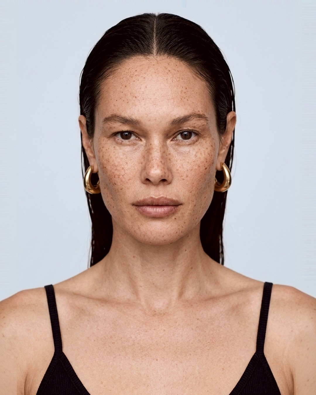 Model portrait, gold hoop earrings, black camisole
